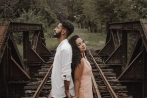 Man and woman standing back to back on bridge