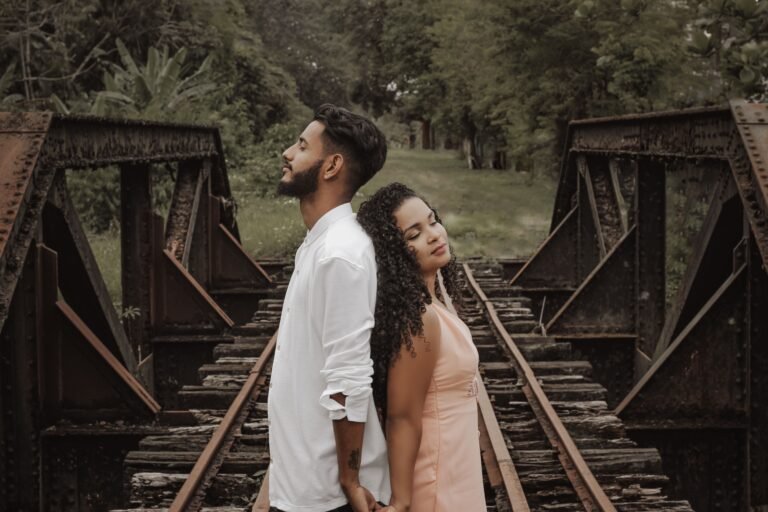Man and woman standing back to back on bridge
