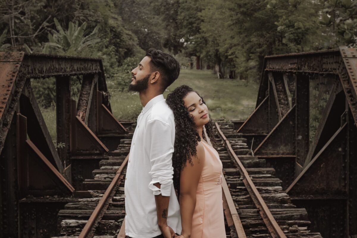 Man and woman standing back to back on bridge