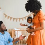 man reaching for baby from mother showing coparenting